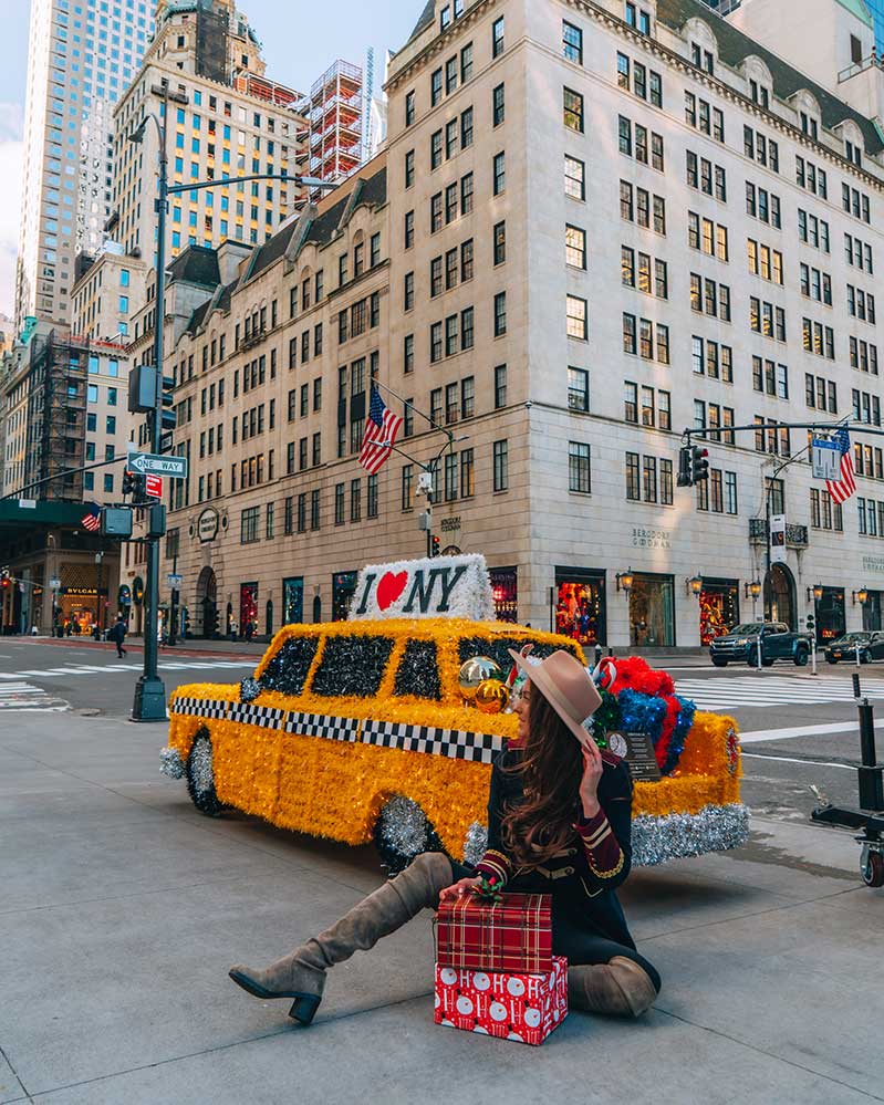 Kristi Hemric (Instagram: @khemric) relaxes in front of the giant sized taxi cab ornament on NYC’s 5th Avenue
